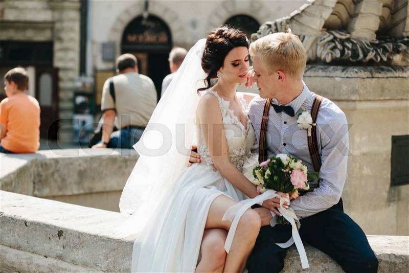 Bride and groom posing at the old fountain, stock photo