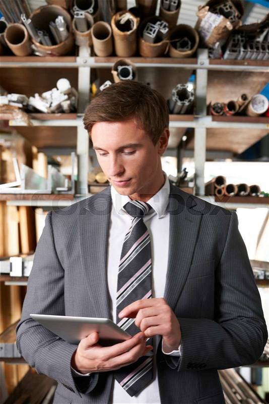 Businessman Checking Stock In Warehouse Using Digital Tablet, stock photo