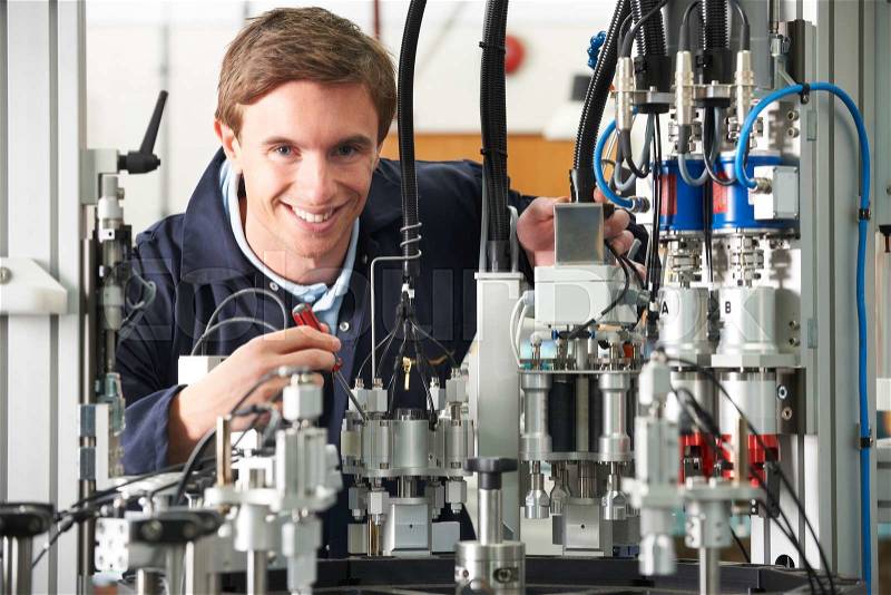 Engineer Working On Complex Equipment In Factory, stock photo