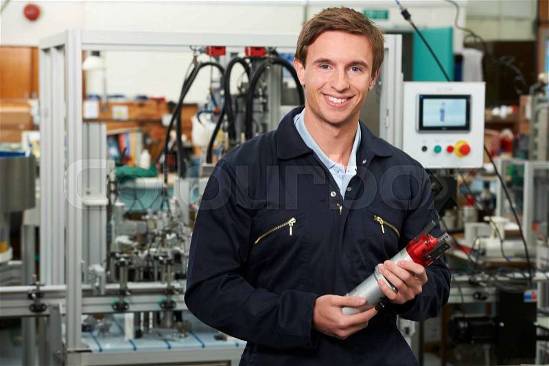 Portrait Of Engineer Holding Component In Factory, stock photo