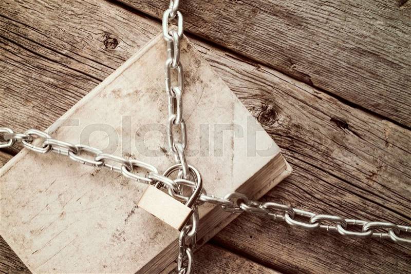 Old book with chain and padlock on wooden background.Vintage style, stock photo