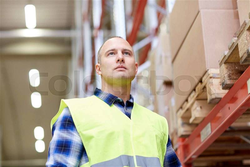 Wholesale, logistic, people and export concept - man in reflective safety vest at warehouse, stock photo