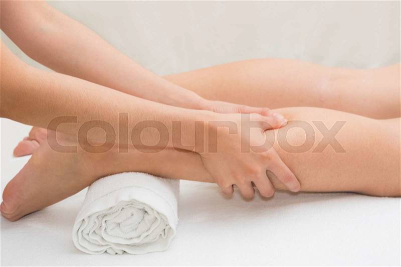 Therapist doing massage on woman leg in day spa, stock photo