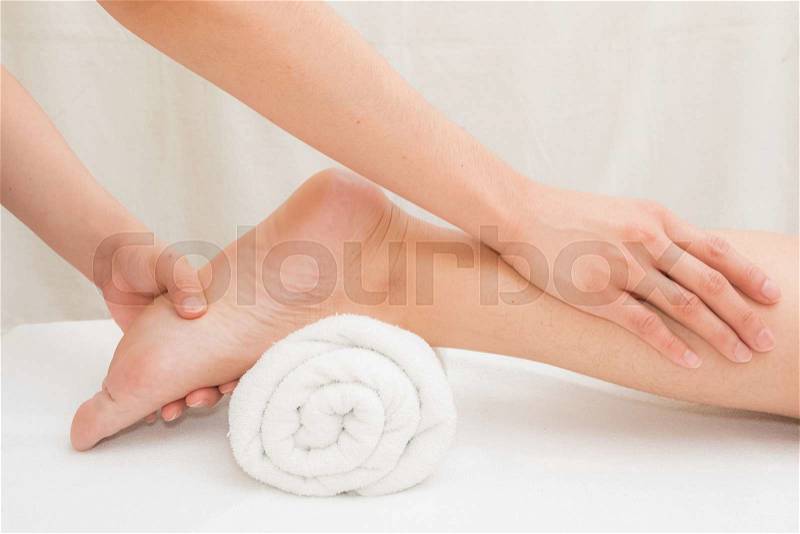 Therapist doing massage on woman leg in day spa, stock photo