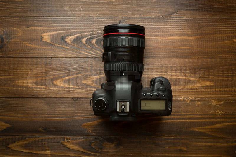 Professional digital camera on dark wooden background, stock photo