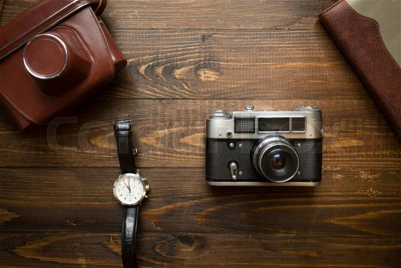 Top view of vintage manual camera, notebook and watches on wooden background, stock photo