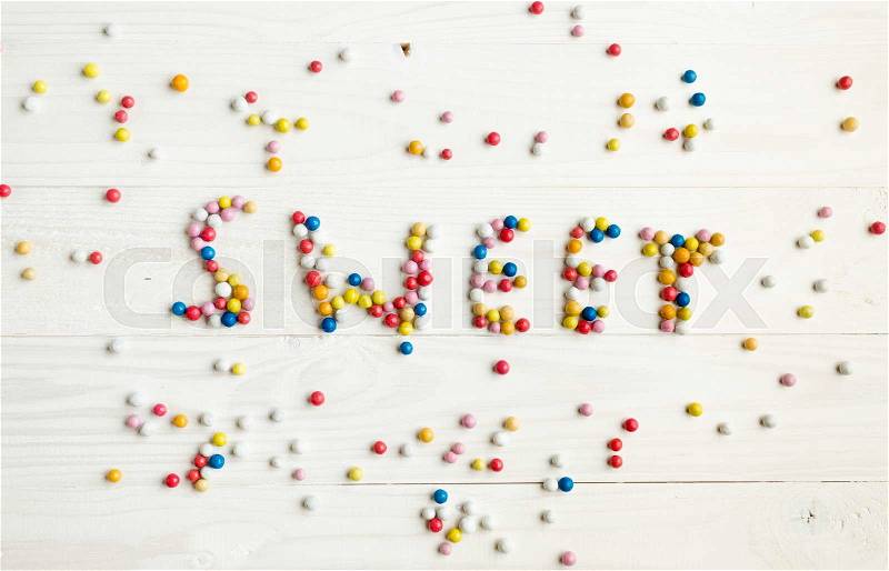 Word Sweet written by little colorful candies on white wooden background, Sweets concept, stock photo