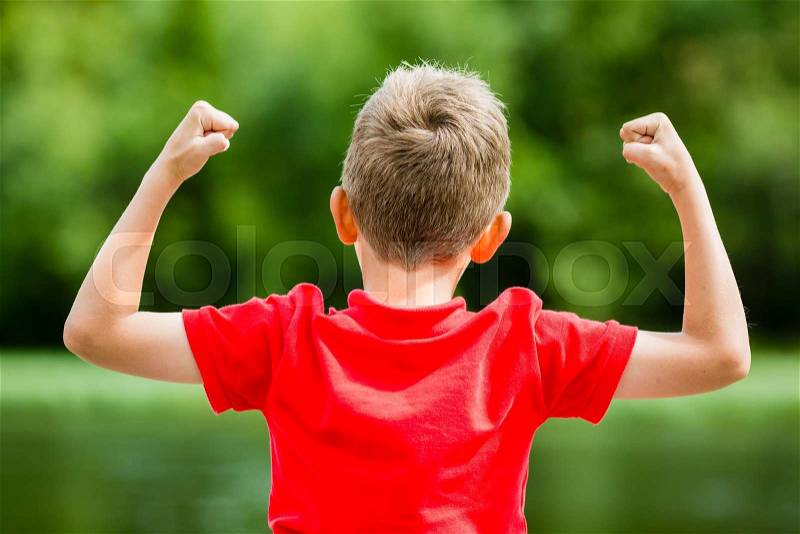 Boy with raised arms and fists in the air celebrating success or victory, stock photo
