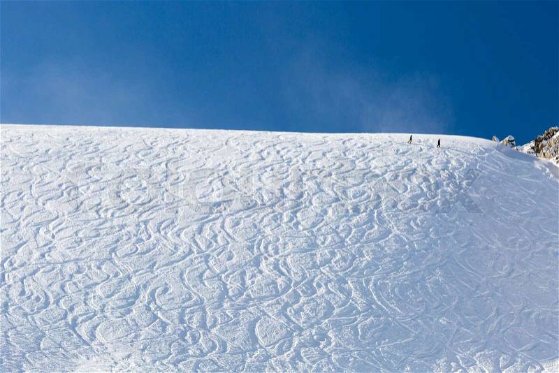 Tracks of off piste skiers in fresh white powder snow on a sunny day, stock photo