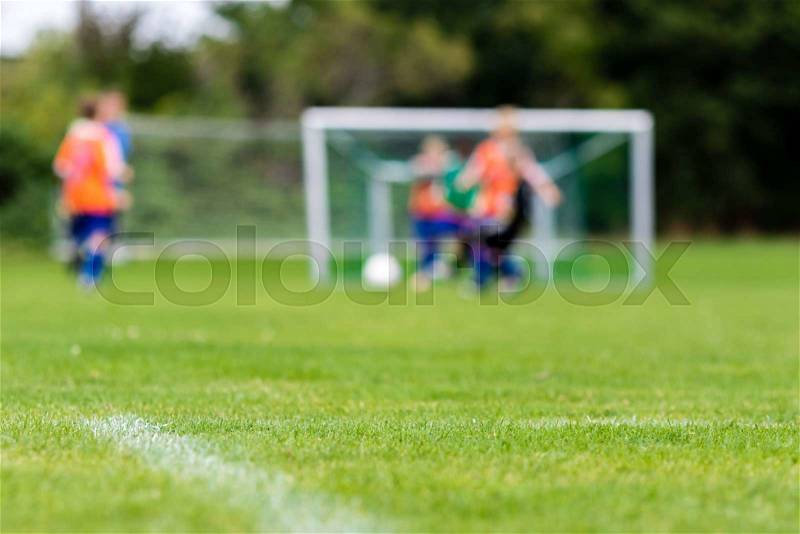 Blurred soccer players playing soccer match on green soccer pitch on sunny summer day, stock photo