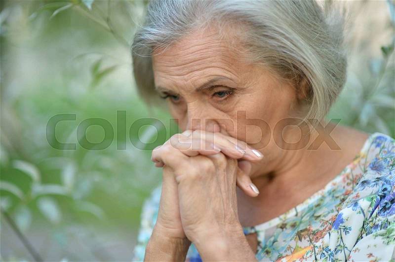 Nice sad old woman on the spring background, stock photo