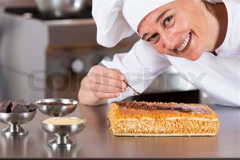 Pastry chef decorating cake yolk and cream, stock photo