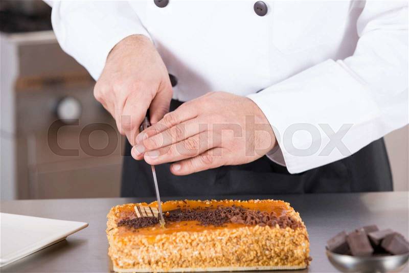 Pastry chef cutting a cake yolk and cream, stock photo