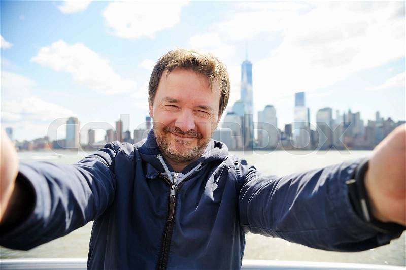 Middle age man making a self portrait (selfie) with Manhattan skyscrapers in New York City, stock photo