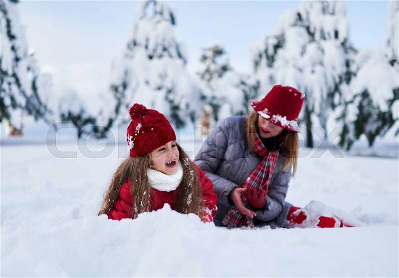 Daughter with mother play in snow-covered park in winter, stock photo