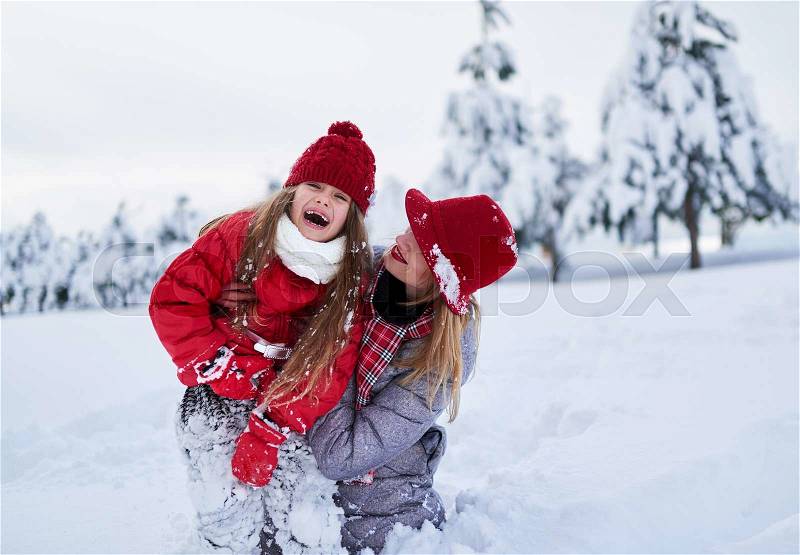 Funny mom and daughter playing in the snow-covered park in winter, stock photo