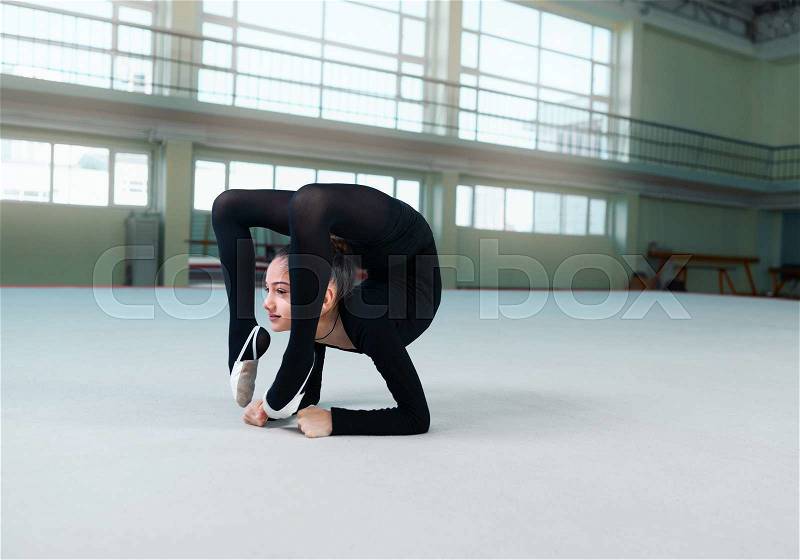 Gymnast performs a back bend on the floor, stock photo