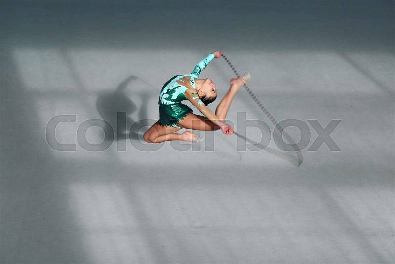 Beautiful gymnast in a green suit jumping rope, stock photo