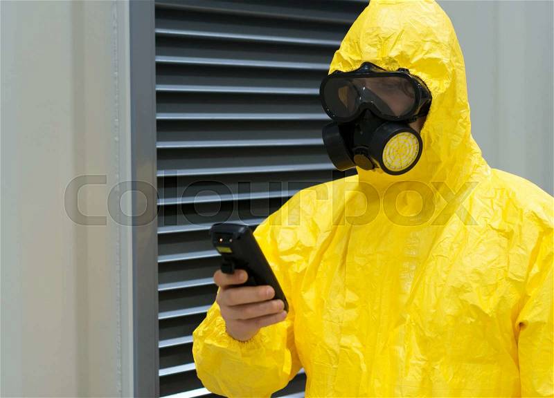Worker in protective chemical suit checking radiation with geiger counter, stock photo