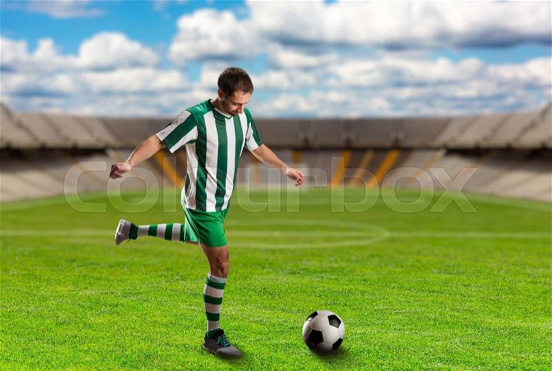 Football player kicking the ball on the football ground, stock photo