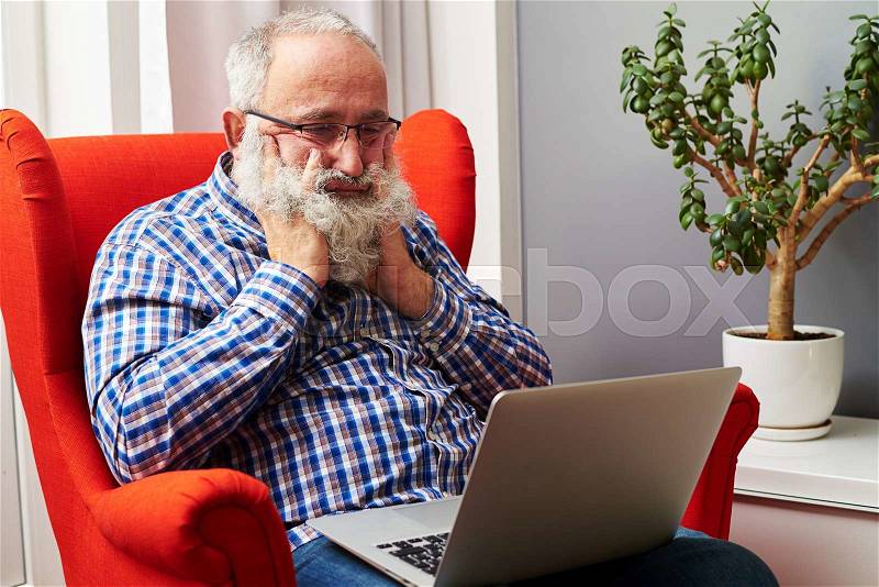 Bearded senior man looking at laptop and boring at home, stock photo