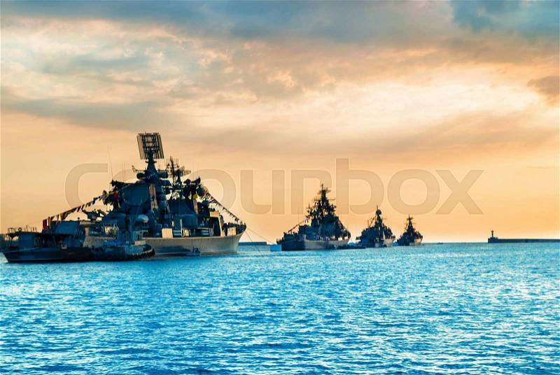 Military navy ships in a sea bay at sunset time, stock photo