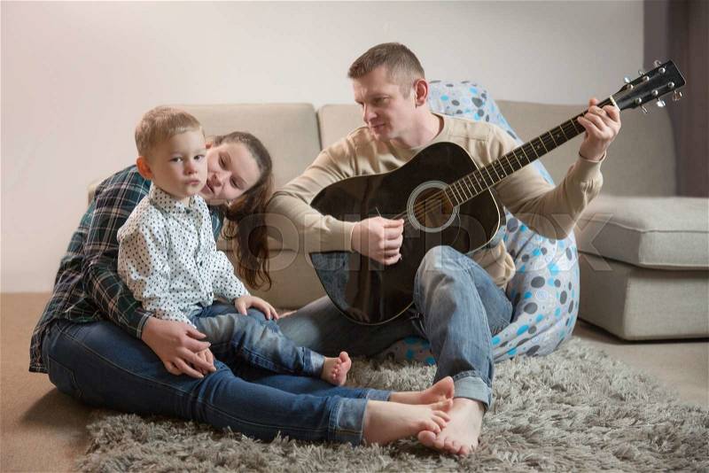Happy father and family playing guitars at home, stock photo