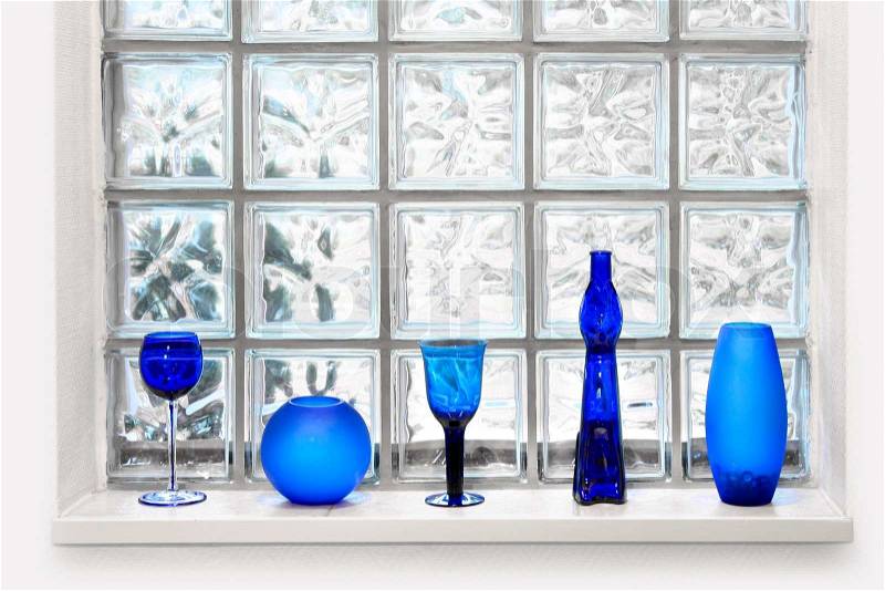 Blue vases and glassed in front of transparent glass tile window, stock photo