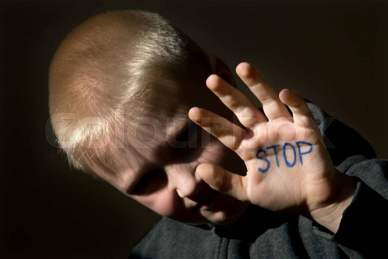 Upset abused frightened little child (boy), stop hand jesture close up horizontal dark portrait with copy space, stock photo