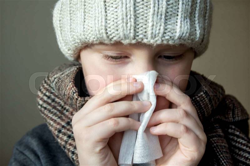 Sick boy (child, kid, teen) blowing his nose , stock photo