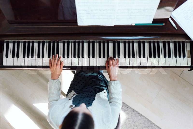 Girl playing on a grand piano, top view, stock photo