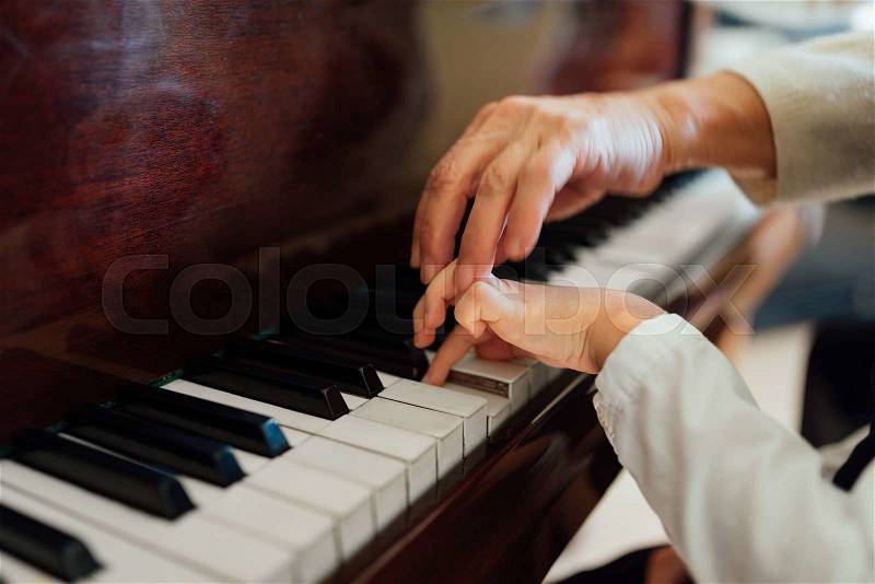 Hand of an experienced pianist, music teacher helping young students, stock photo