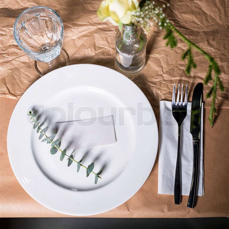 Decorated table ready for dinner. Beautifully decorated table set with flowers, plates and serviettes for wedding or another event in the restaurant, stock photo