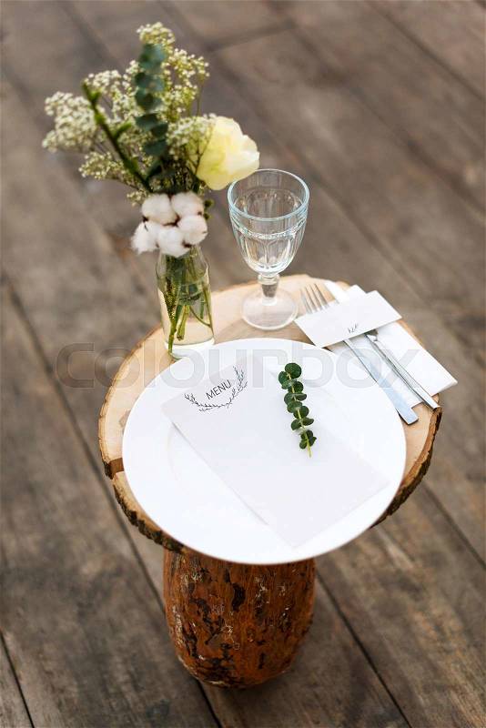 Paper menu on decorated table ready for dinner. Beautifully decorated table set with flowers, plates and serviettes for outdoor wedding ceremony or another event in the restaurant. Selective focus, stock photo