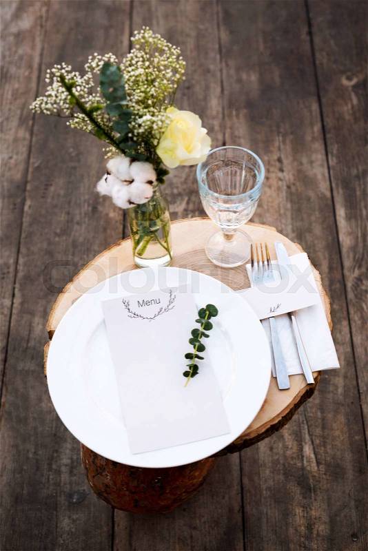 Paper menu on decorated table ready for dinner. Beautifully decorated table set with flowers, plates and serviettes for outdoor wedding ceremony or another event in the restaurant, stock photo