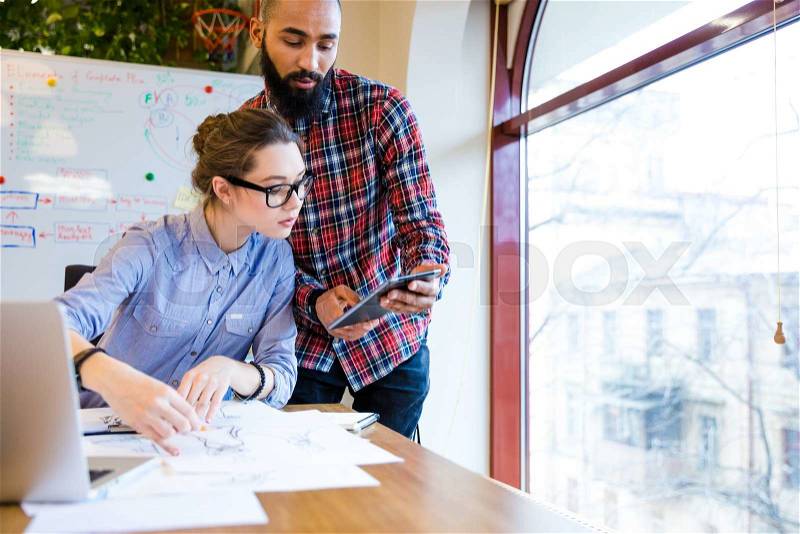 Two young woman and man fashion designers working and using tablet together , stock photo