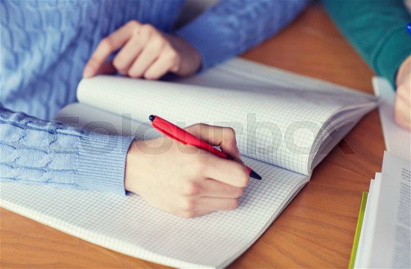 People, learning, education and high school concept - close up of female student hands writing to notebook, stock photo