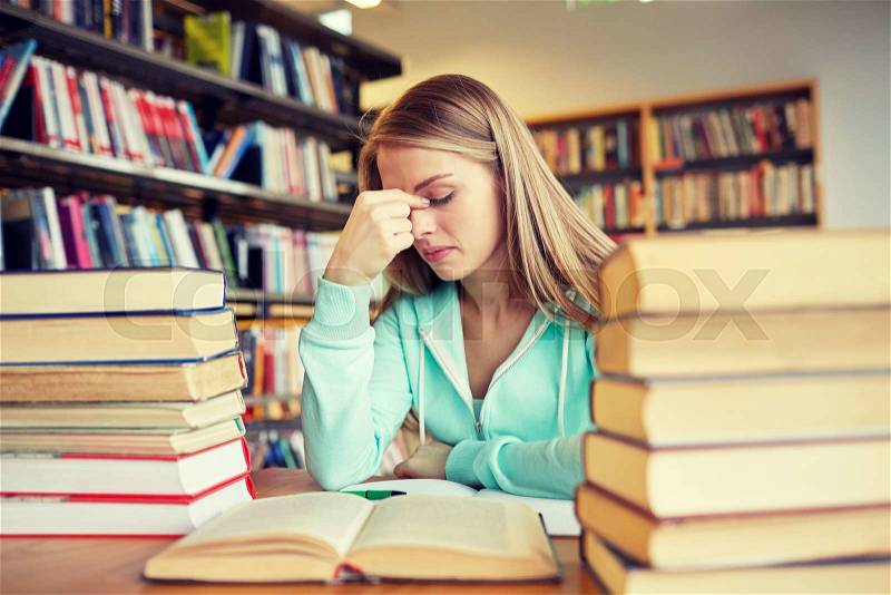 People, knowledge, education, literature and school concept - bored student girl or young woman with books dreaming in library, stock photo