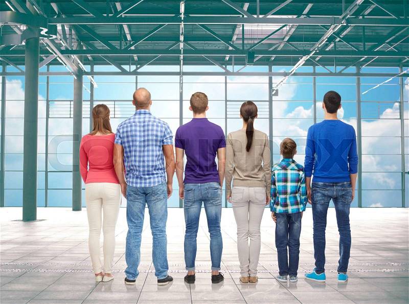Travel, vacation and people concept - group of happy people or big family from back over airport terminal window and sky background, stock photo