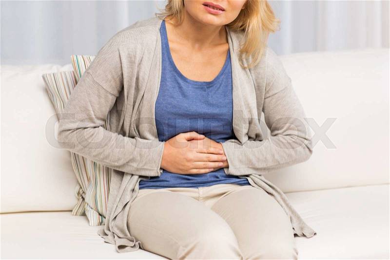 People, healthcare and problem concept - close up of unhappy woman suffering from stomach ache at home, stock photo