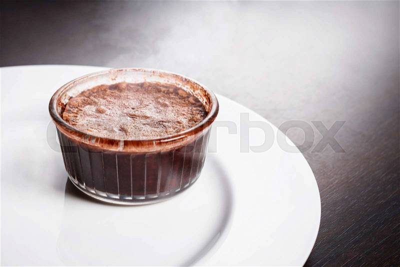 Freshly baked steaming hot dessert chocolate fondant lava cake served on white plate. Famous French dessert on dark wooden table top view, stock photo