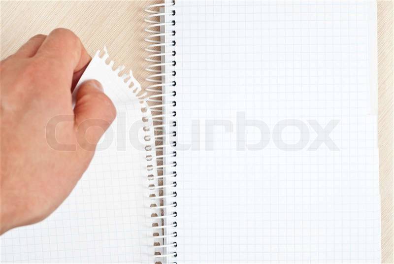 Hand tearing one paper page from notepad on desk, stock photo