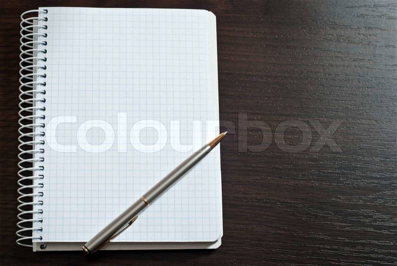 Blank spiral note pad with silver pen on wood, stock photo