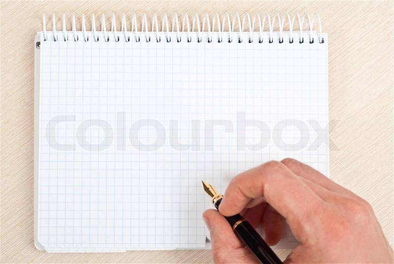 Male hand holding a pen writing notes in a notebook, stock photo