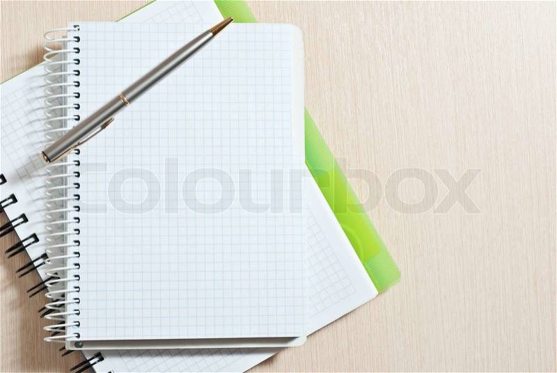 Blank spiral note pad with silver pen on wood desk, stock photo