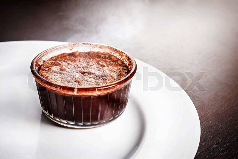 Freshly baked steaming hot dessert chocolate fondant lava cake served on white plate. Famous French dessert on dark wooden table top view, stock photo