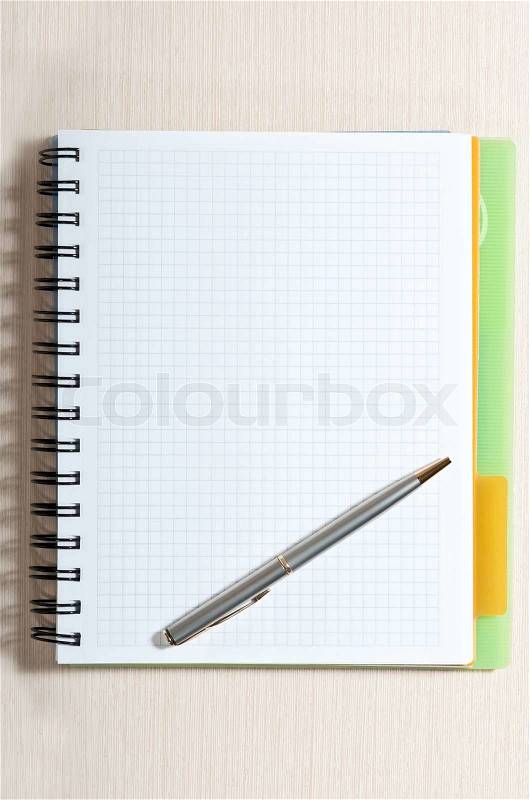 Blank spiral note pad with silver pen on wood desk, stock photo