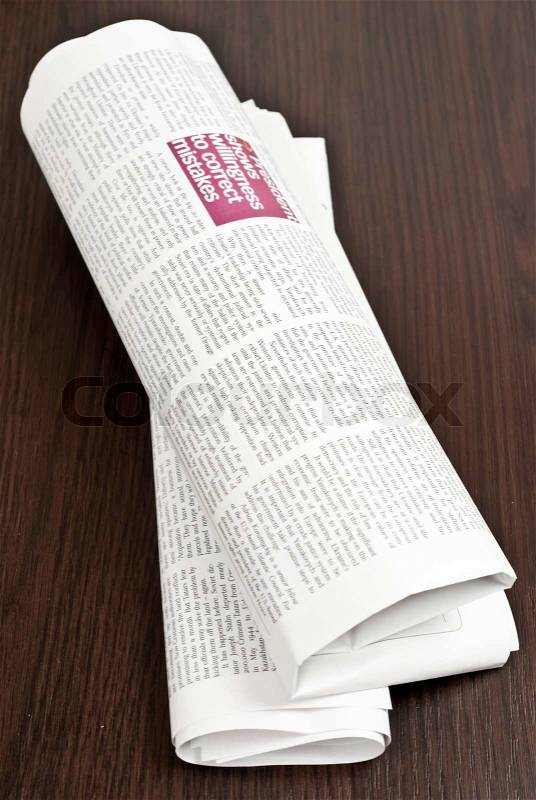Rolled newspaper on wood dark table, stock photo