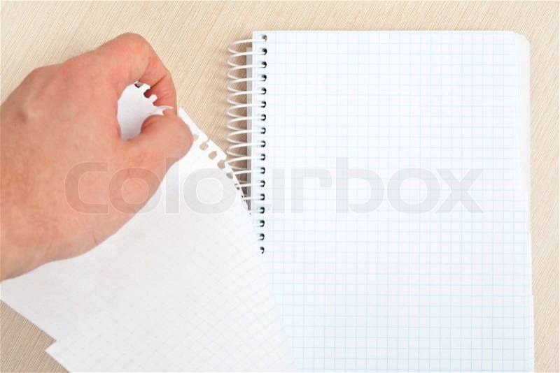 Hand tearing one paper page from notepad on desk, stock photo