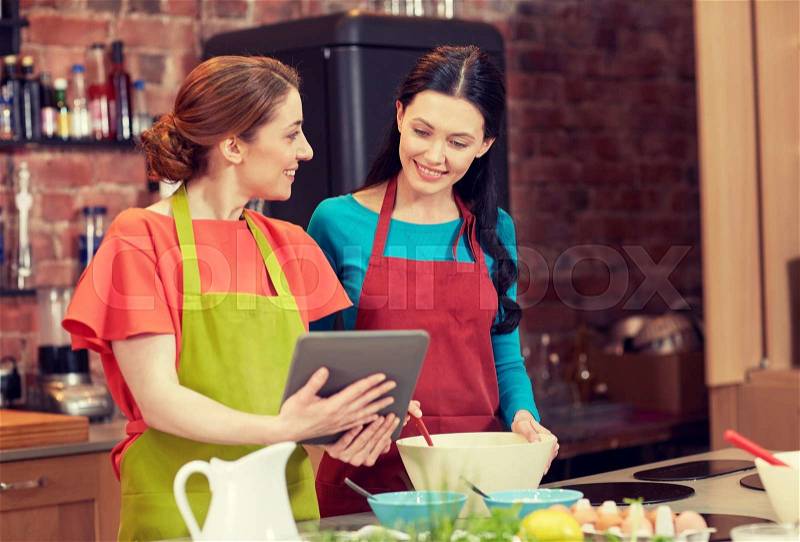 Cooking class, friendship, food, technology and people concept - happy women with tablet pc computer in kitchen, stock photo